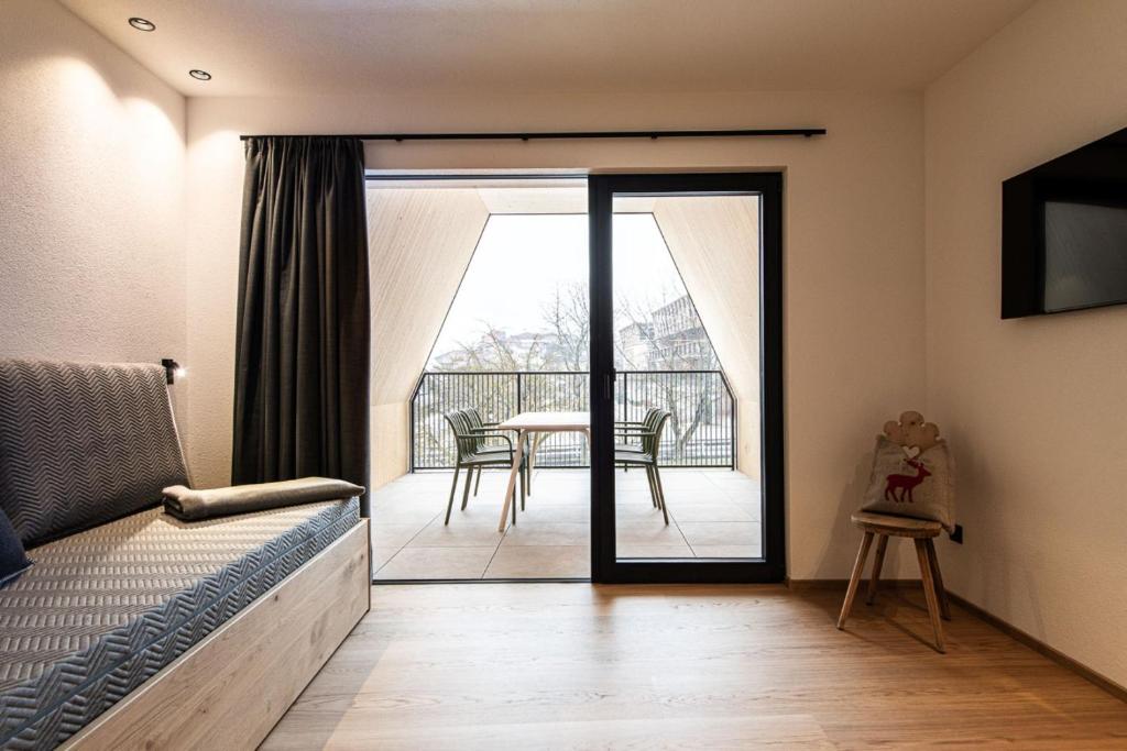 a bedroom with a bed and a balcony with a table at Senner Nature Stay in Riscone