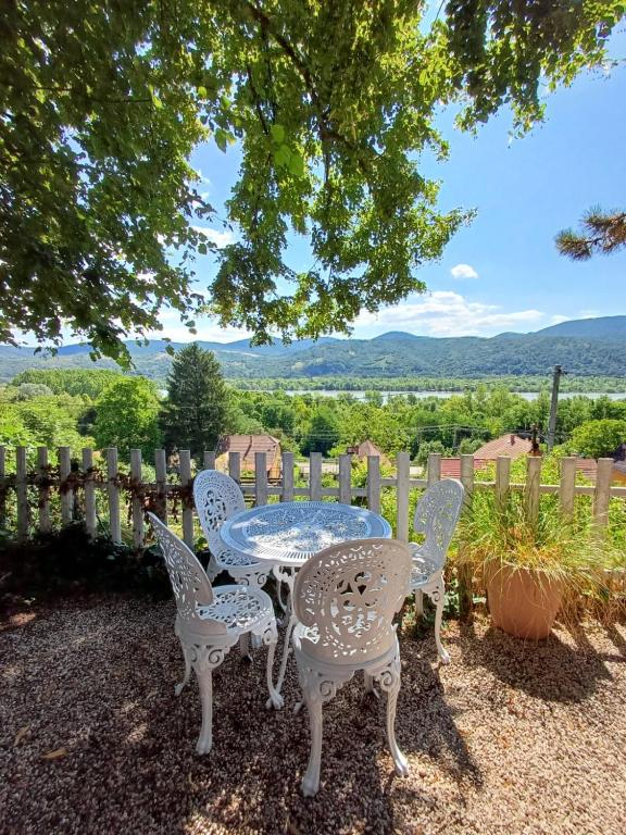 a table and chairs with a view of the mountains at Fecskefészek vendégház in Nagymaros