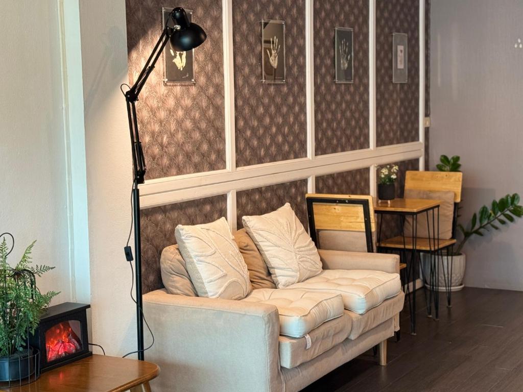 A softly furnished lounge with a sofa, reading lamp and decorative fireplace.