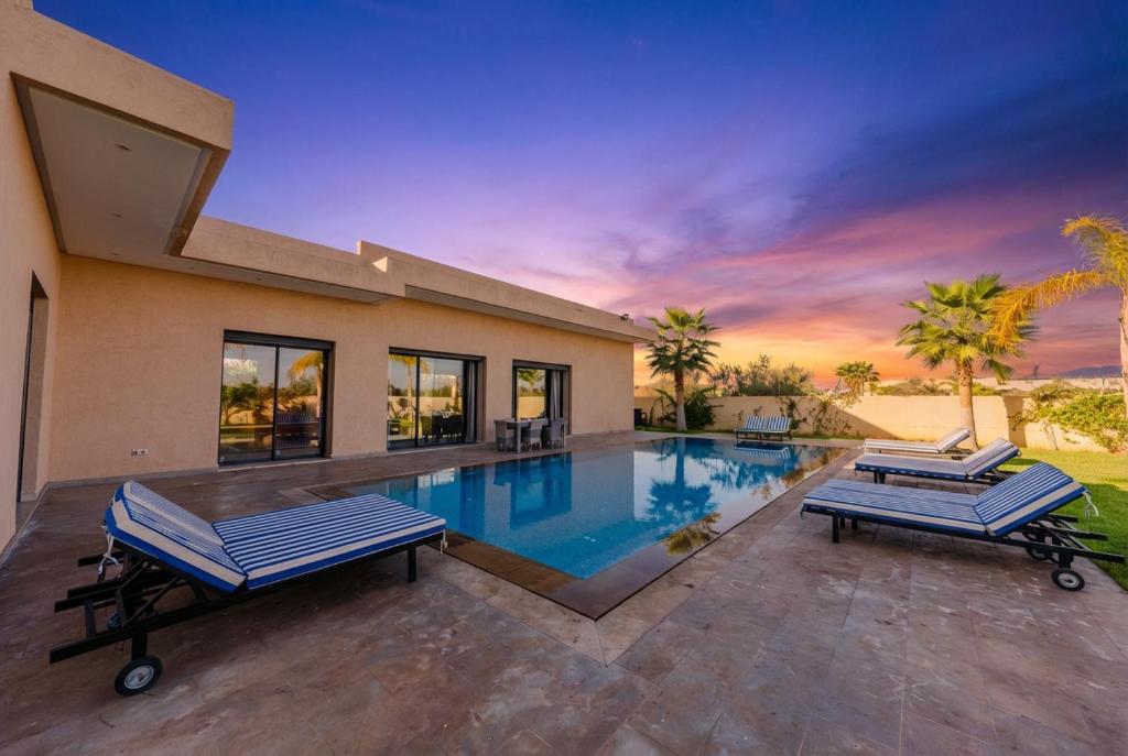 a house with a swimming pool with two lounge chairs at Villa Dar E'Zwinna in Marrakesh