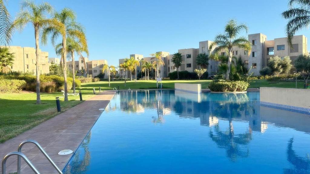 a large swimming pool with palm trees and buildings at La Perle de Marrakech in Marrakesh