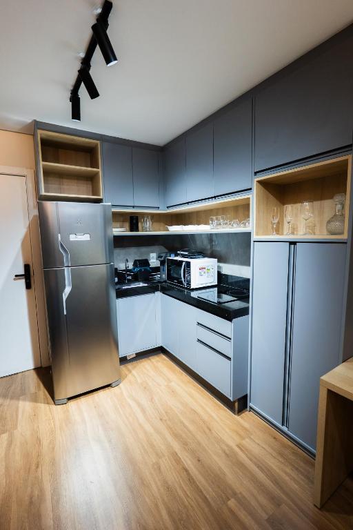 a kitchen with stainless steel appliances and wooden floors at Flat exclusivo Studio Cuiabá 1207 in Cuiabá