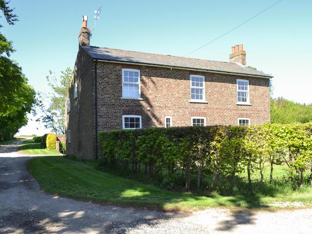 a brick house with a hedge in front of it at The Hind House in Cowlam
