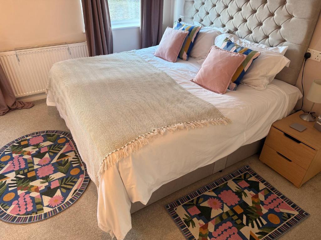 a bedroom with a bed with pillows and two rugs at Cosy Flat, close to Bath Rugby and City Centre in Bath