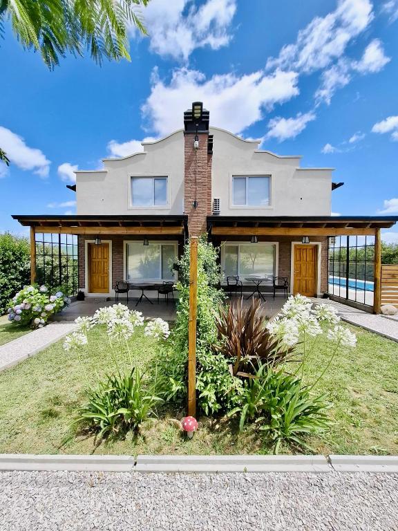 a house with glass doors and flowers in a yard at Lirios del Cerro in Sierra de la Ventana
