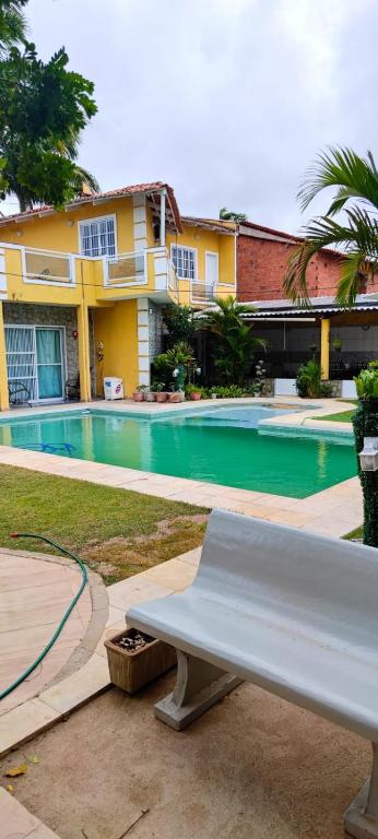 a white bench sitting in front of a swimming pool at Casa inigualavel in Caucaia