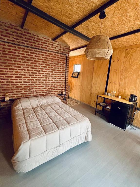 a bedroom with a large bed and a brick wall at Alamos in Puerto Madryn