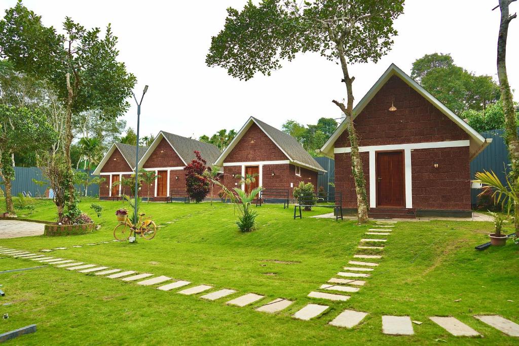 a group of bungalows in a yard withgrass at Misty Forest Resort Wayanad in Wayanad