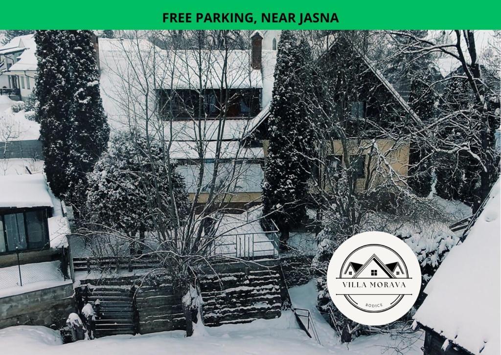 a building covered in snow with a sign that reads free parking new akka at Vila Morava in Liptovský Mikuláš