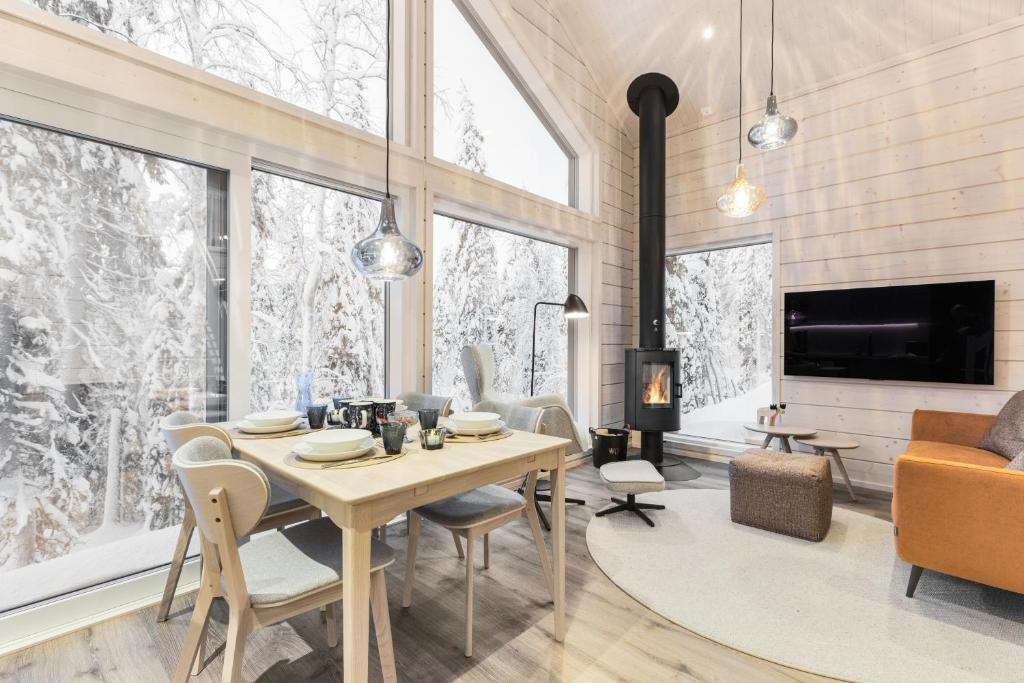 a dining room with a table and chairs and a fireplace at Villa Mokum by PolarVillas in Kittilä