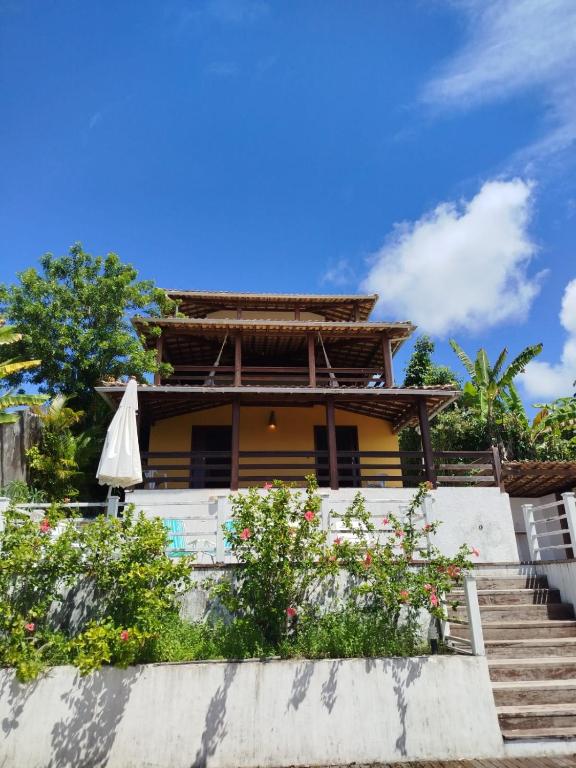 a house with an umbrella and some flowers at Varanda das Palmeiras in Cairu