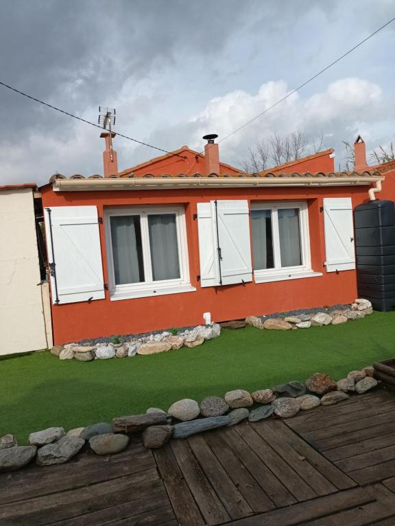 an orange house with a green lawn in front of it at Maison de pêcheur in Marseillan