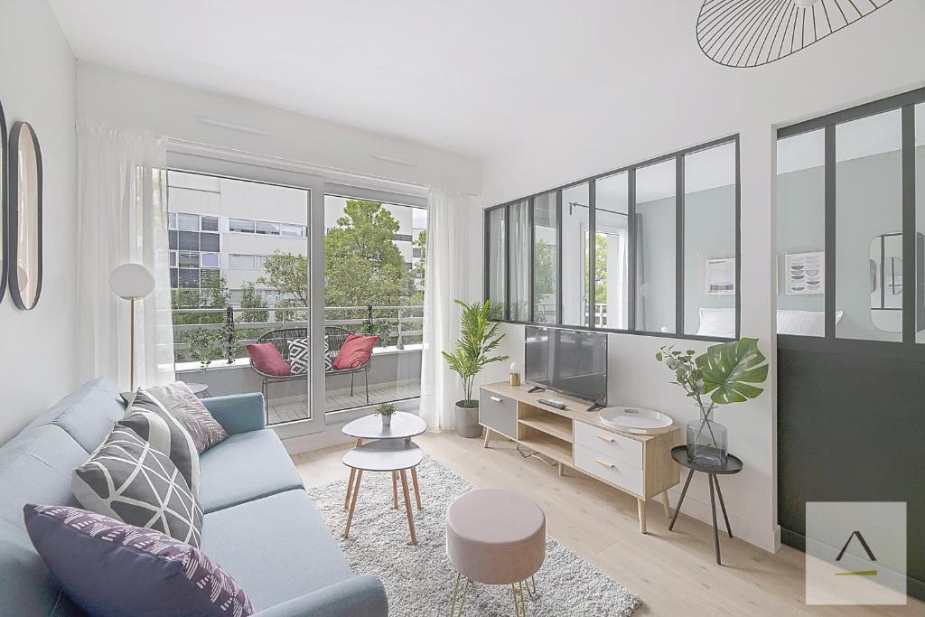 ein Wohnzimmer mit einer blauen Couch und einem Fernseher in der Unterkunft Le Mirabeau in Rennes