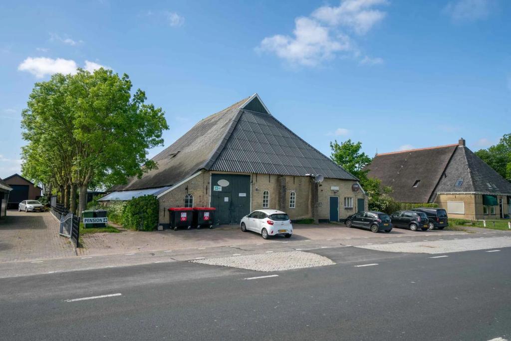 a large barn with a car parked in front of it at Pension Veldzigt in Wijnaldum