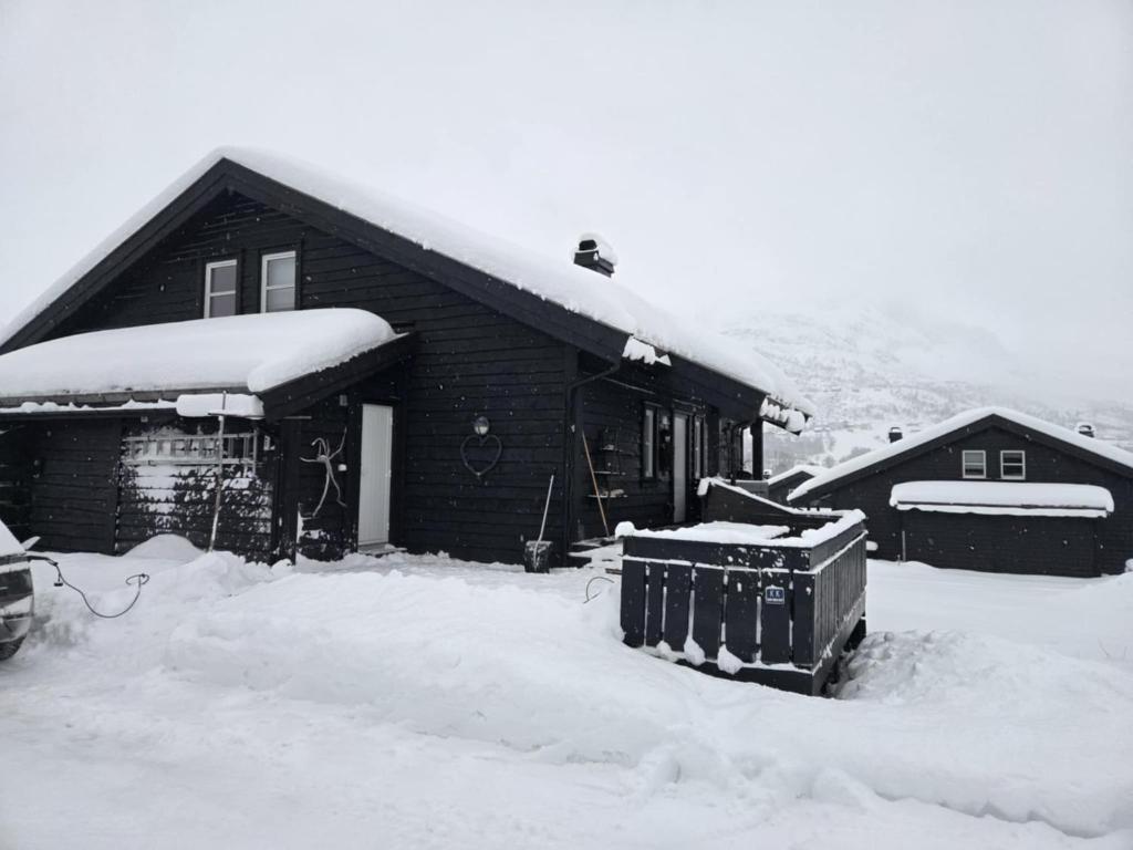 a house covered in snow next to a building at Ski-In, Ski-Out apartment at Filefjell in Tyinkrysset