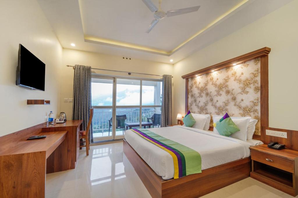 a bedroom with a large bed and a large window at Treebo Windsong Resort Munnar, Tea Plantation View in Munnar