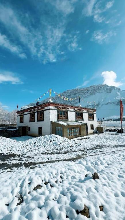 a building with snow on the ground in front of it at Daar home stay in Kaja
