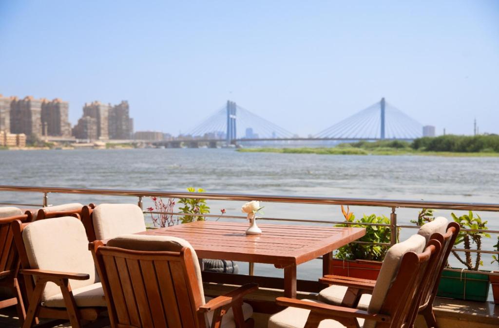 a table and chairs on a balcony with a view of the river at Nile Transport Hotel in Cairo