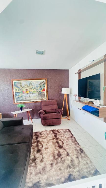 a living room with a couch and a tv at Casa com piscina in Paulista