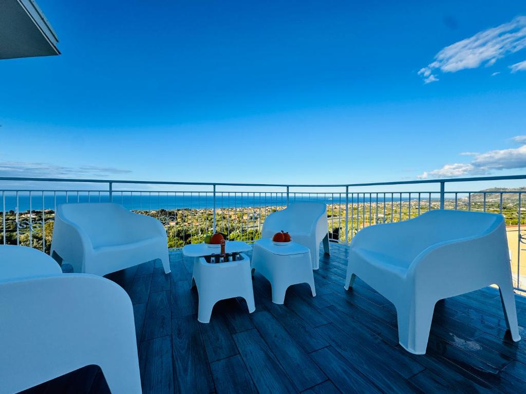 a balcony with white tables and chairs and the ocean at Al Grande Pino - Private pool, Jacuzzi and amazing Sunset in Campofelice di Roccella