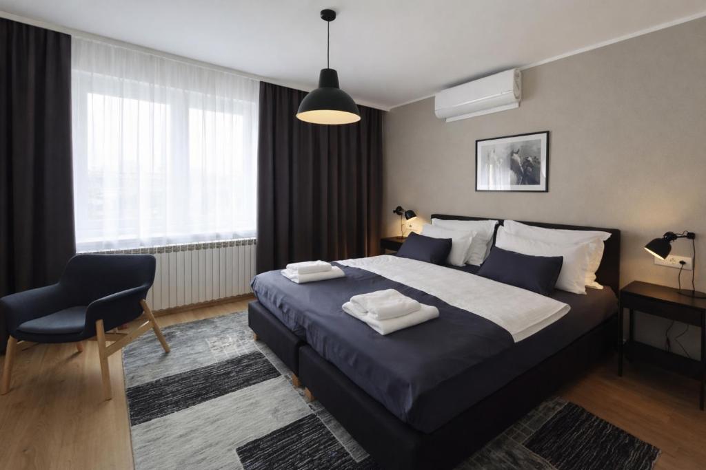 a bedroom with a bed and a chair and a window at Apartman Relax in Đakovo