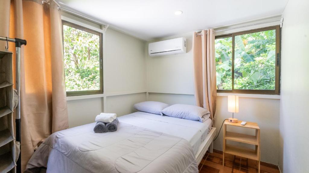 a small bedroom with two beds and two windows at GALA Santa Teresa Studios - Walk to Beach & Surf in Santa Teresa Beach