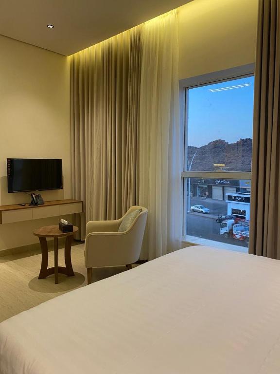 a hotel room with a bed and a chair and a window at شقق نيفا المخدومة in Hail