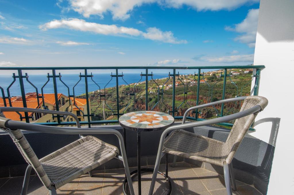 ein Balkon mit zwei Stühlen, einem Tisch und Aussicht in der Unterkunft Sunset Star with Sea View in Calheta