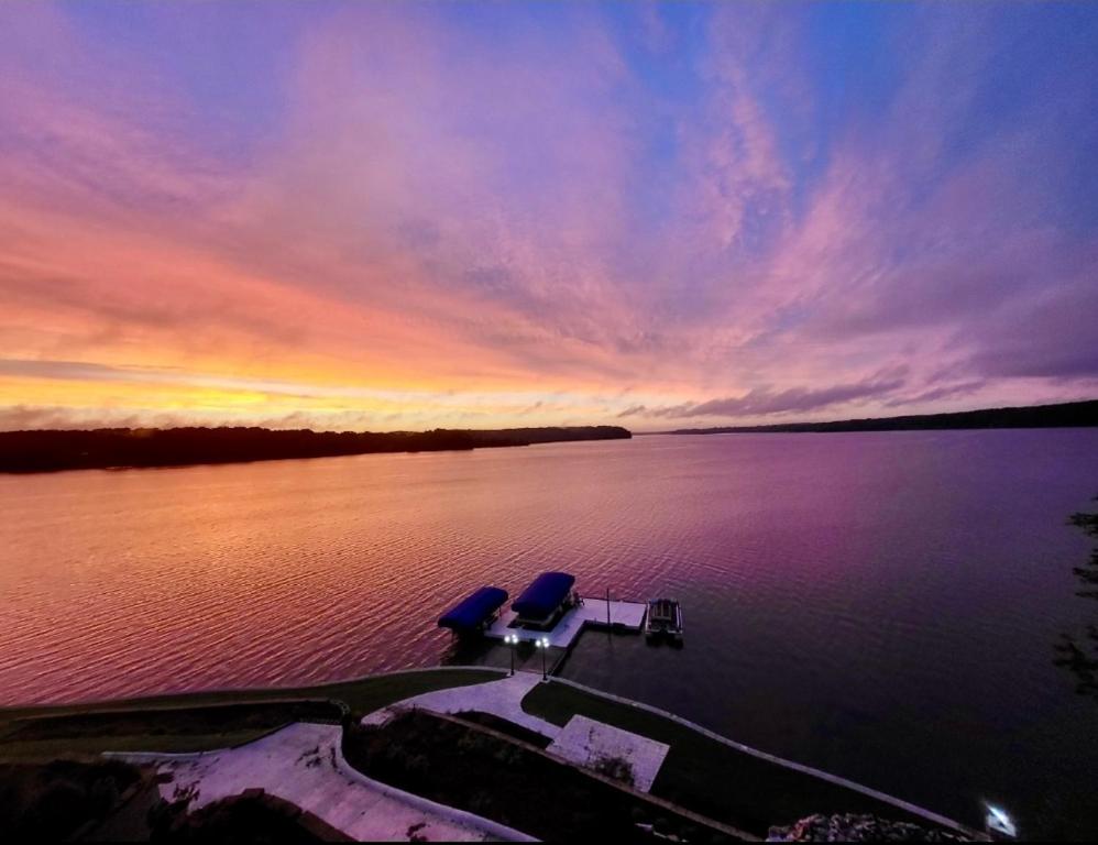 a boat in a body of water with a sunset at Lake Oconee Waterfront Apartment in Greensboro