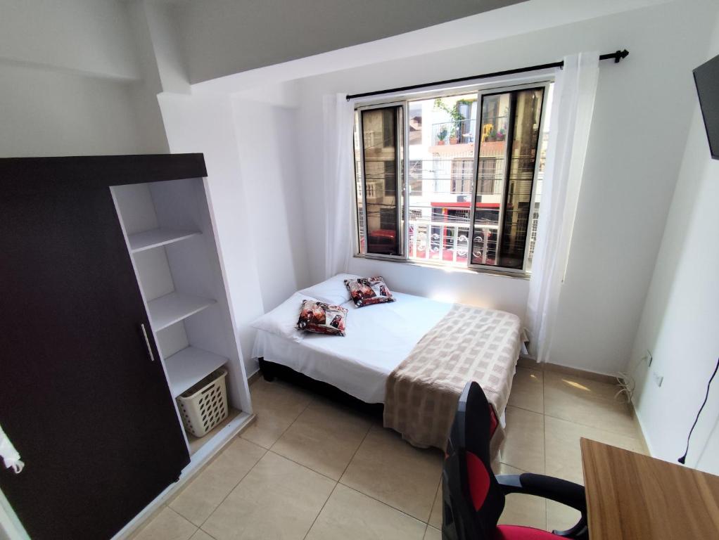 a small bedroom with a bed and a window at Edificio Wil Hostal Apt 201 in Cali