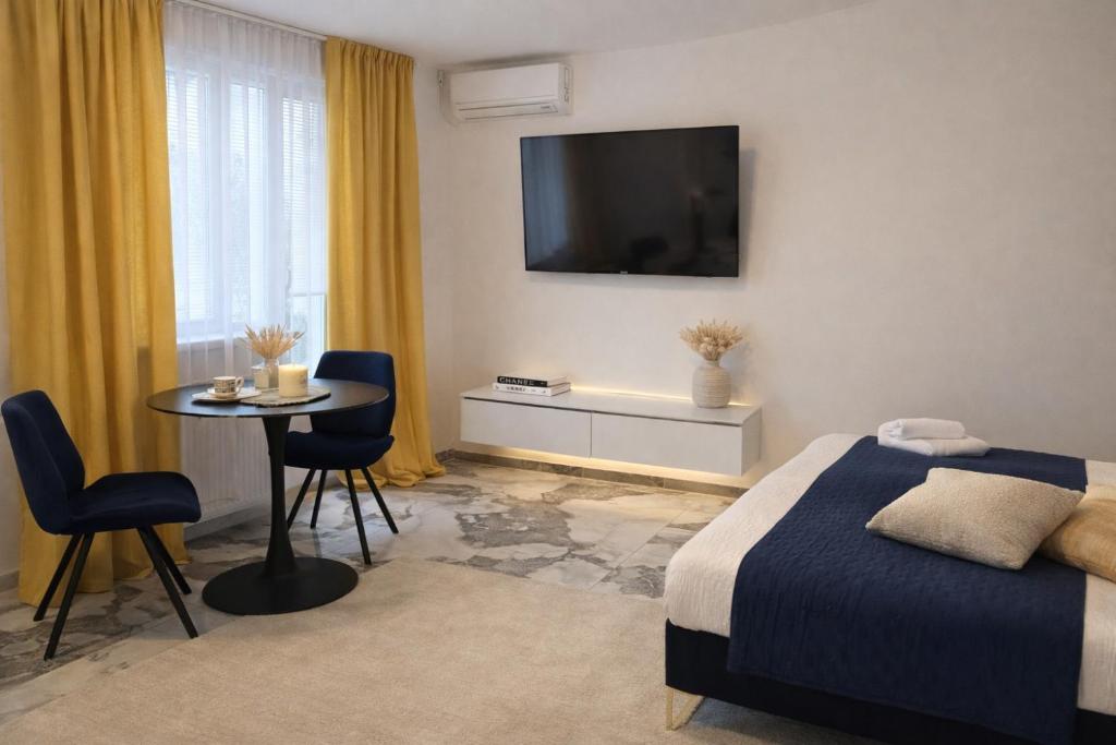 a bedroom with a bed and a table and a television at Apartman VEMY in Trnava