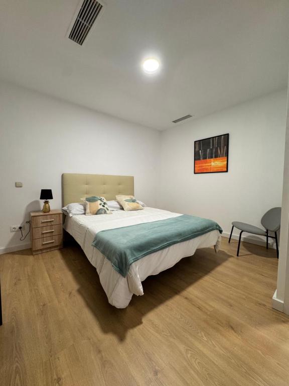 a bedroom with a large bed and a chair at Apartamentos Melisa - Madrid in Madrid