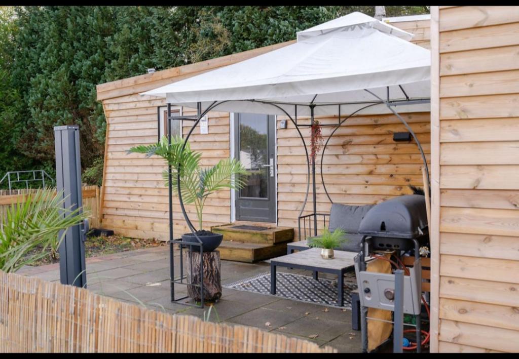a patio with an umbrella and a grill at Chalet Timber -close to the woods in Anloo