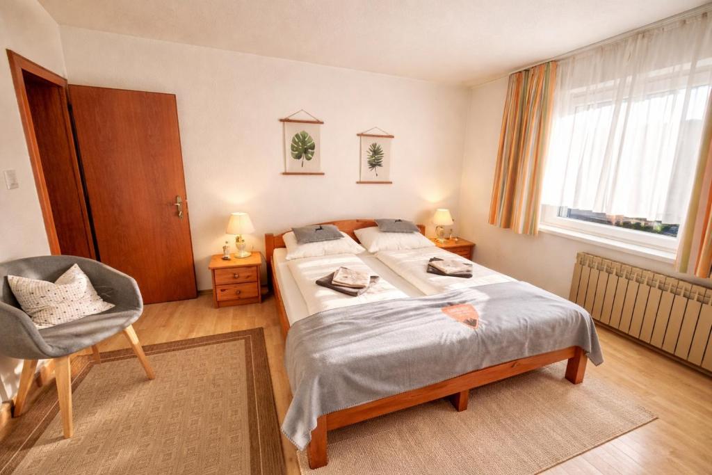 a bedroom with two beds and a chair and a window at Haus Greif in Weissenbach am Lech