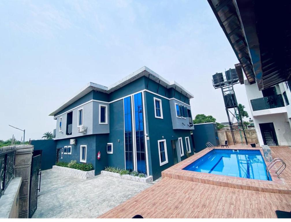 a blue building with a swimming pool in front of it at Wesmont Hotels in Ikorodu