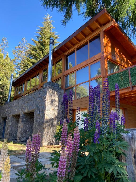 a house with purple flowers in front of it at Maria del Bosque Apart Hotel / Cabañas in San Carlos de Bariloche