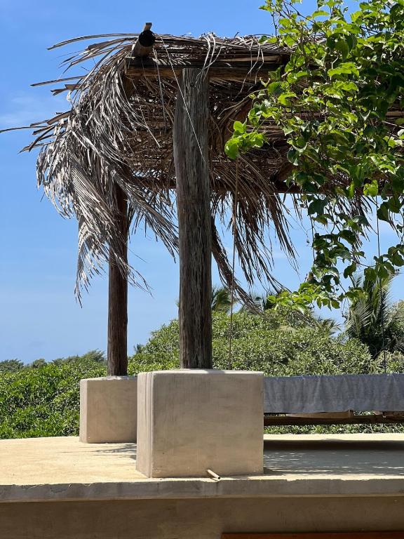 a bird sitting on top of a straw roof at Casa Chukum - Retreat House - Agua Blanca in Playa Agua Blanca