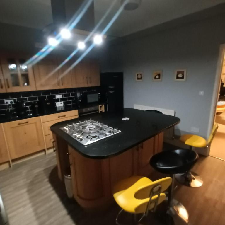 a kitchen with a black counter and yellow chairs at Foxy stays in Tanfield