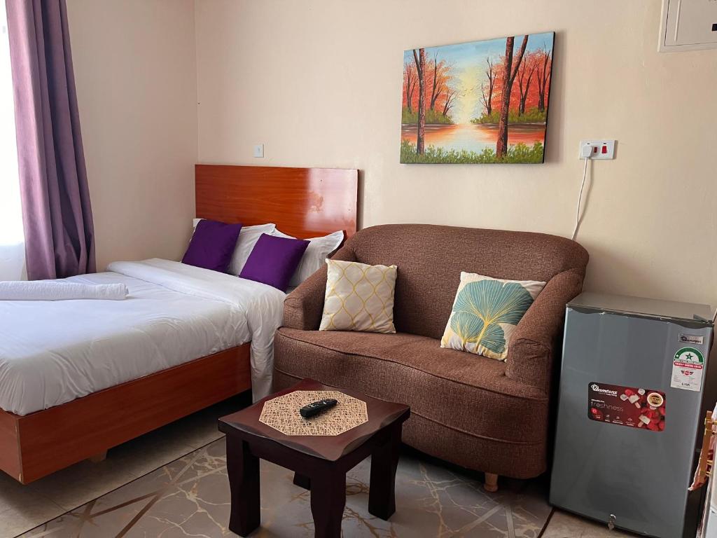 a room with a bed and a couch and a chair at Pearl Studio in Machakos
