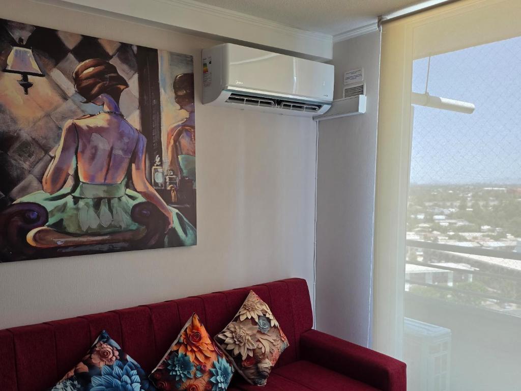 a living room with a red couch in front of a painting at Dpto 2D 2B con y sin estacionamiento in Santiago