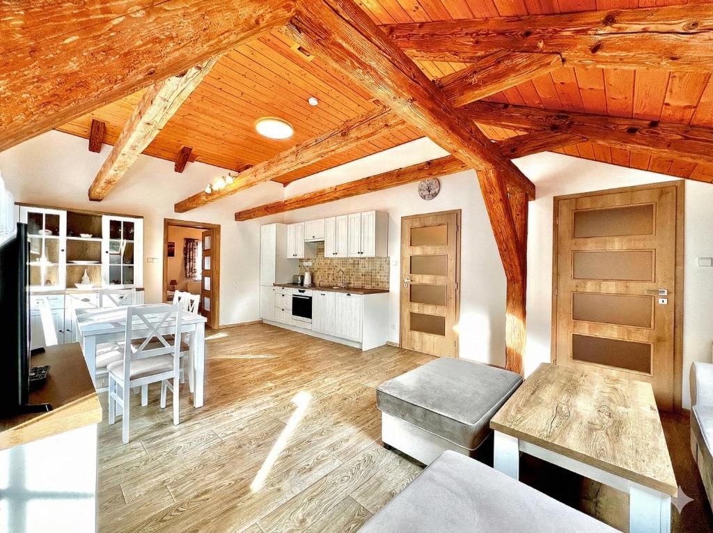 a kitchen and living room with wooden ceilings and a table at Apartmán Jizerské údolí in Kořenov