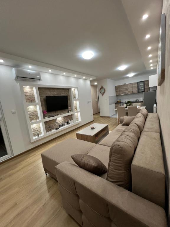 ein Wohnzimmer mit einer großen Couch und einem Fernseher in der Unterkunft Gold Star Apartman in Ruma