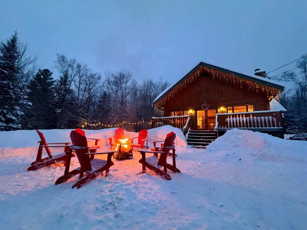 a group of people sitting around a fire in the snow at Chalet Le Crépuscule SPA, BILLARD, FOYER, SENTIERS PRIVES in Chertsey