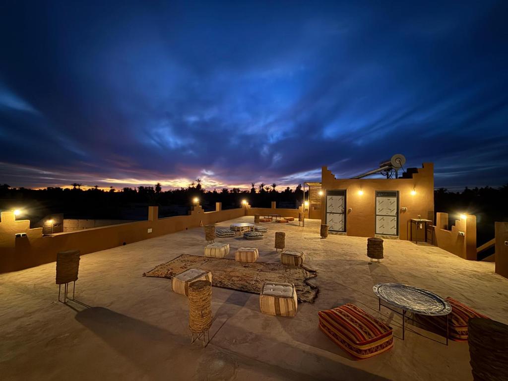 a rooftop patio with tables and chairs at night at Dar Talhaya in Oulad Driss