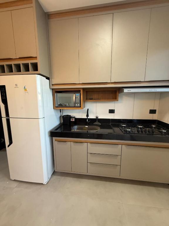 a kitchen with a white refrigerator and a sink at Brisa Mar Prime in Porto Seguro