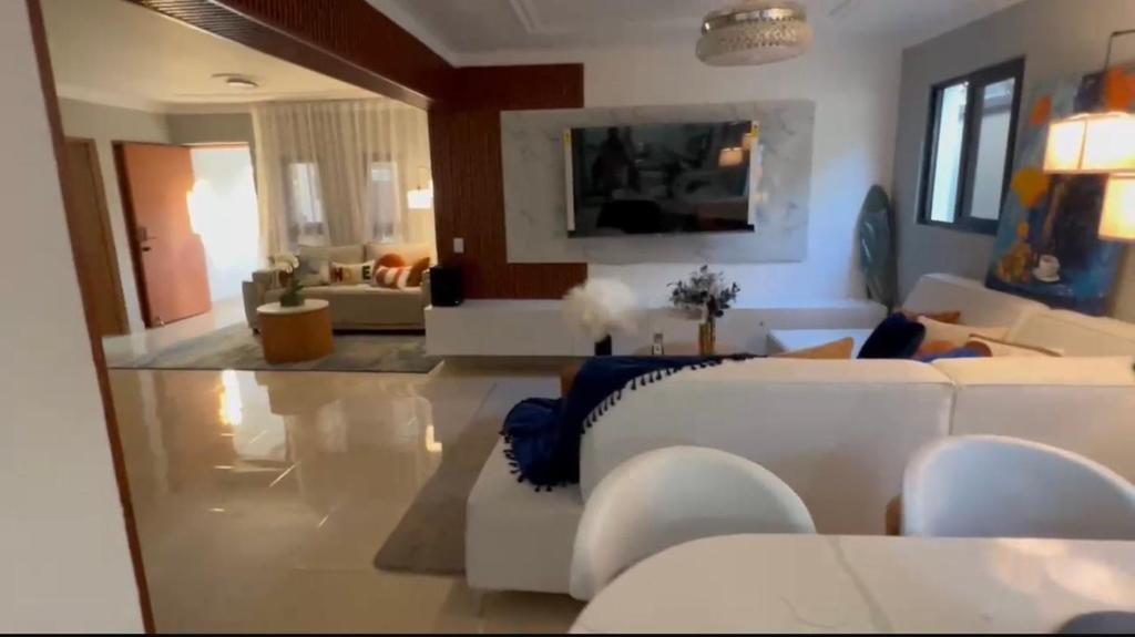 a living room with white couches and a tv at Dgomez House in Santiago de los Caballeros