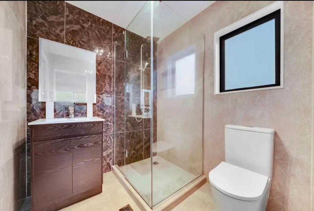a bathroom with a toilet and a glass shower at Unique homestay in Auckland