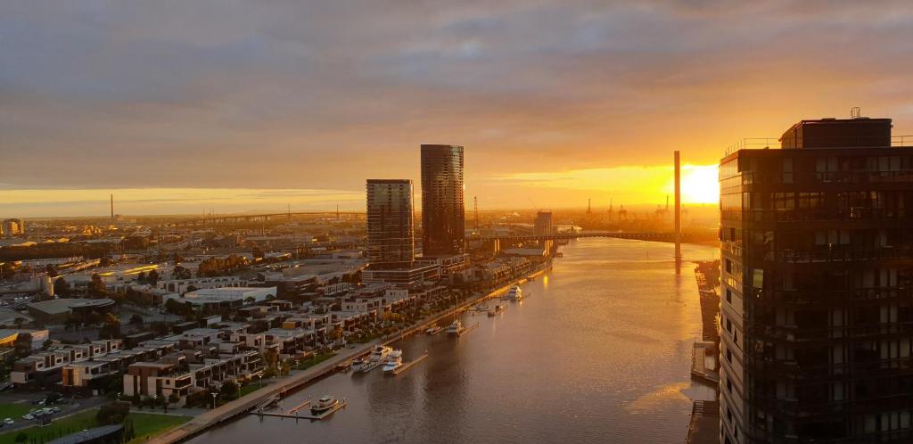 a sunset over a city with a river and buildings at Melbourne Lifestyle Apartments - Best Views on Collins in Melbourne