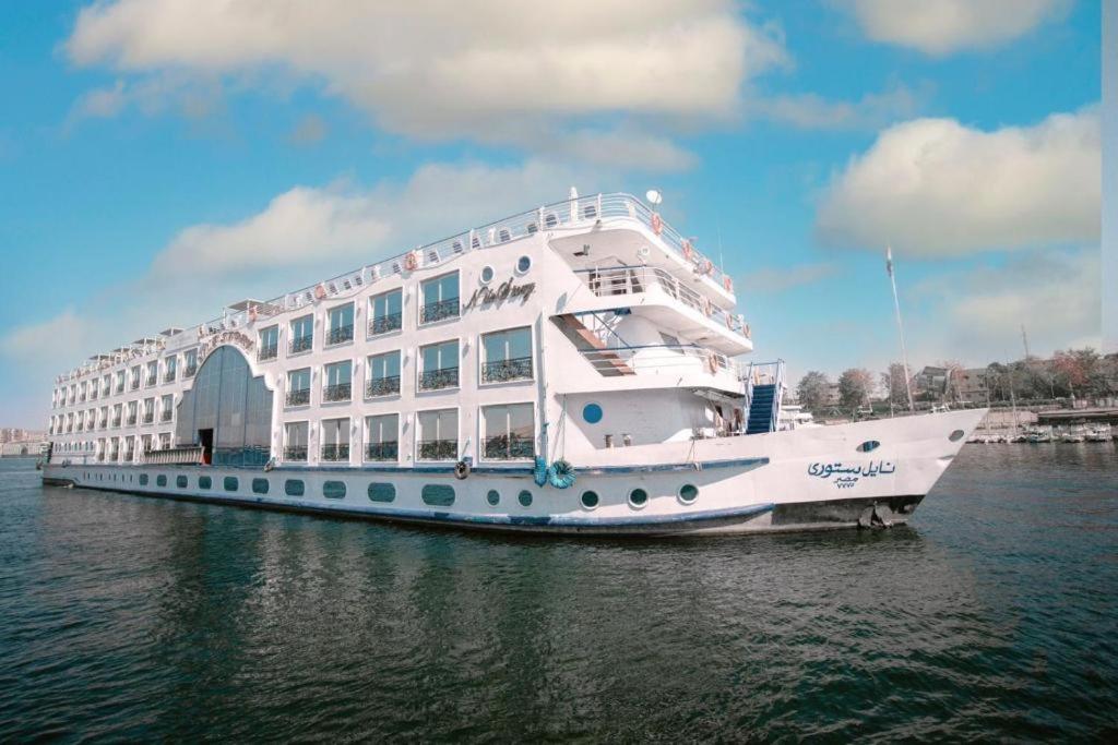 a large white boat in the water next to a building at فندق نايل ستوري سوهاج in Sūhāj