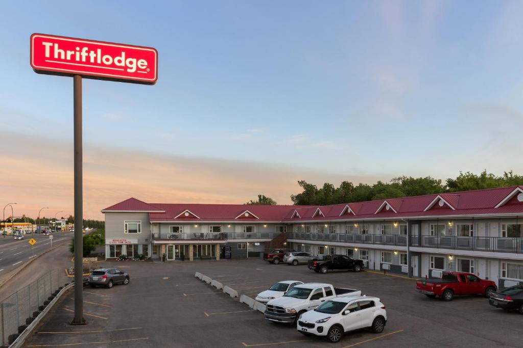 un hôtel avec des voitures garées dans un parking dans l'établissement Thriftlodge Saskatoon, à Saskatoon